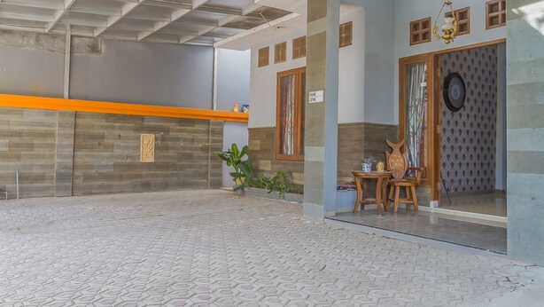 A reception area with a tiled floor, a reception desk, and a seating area with chairs and a table. - RedDoorz Syariah @ Puri Kalijaga Street (Cirebon)