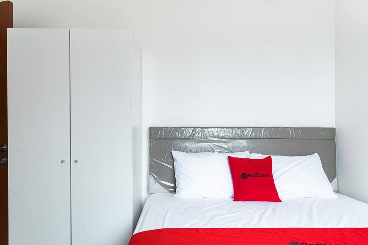 A hotel room with a bed, a wardrobe, and a headboard.