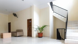 A spacious lobby with a staircase, a potted plant, and a sofa. - RedDoorz Syariah near Purwosari Train Station (Surakarta)