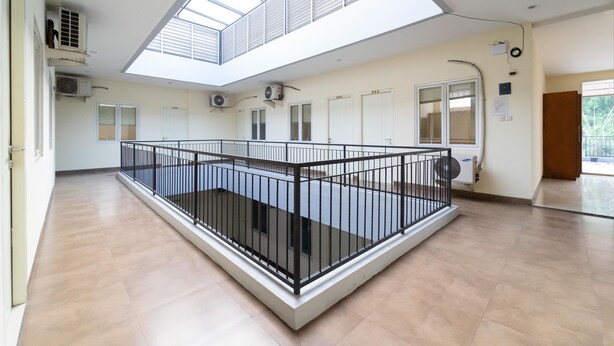 A spacious indoor area with a high ceiling, skylight, and a central black metal railing.