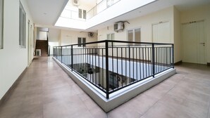 A spacious atrium with a central open area, a staircase, and a balcony with a black railing.