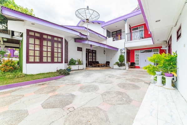 A two-story house with a patio area, a satellite dish, and potted plants.
