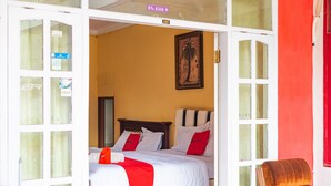 A hotel room with a bed, a chair, and a painting on the wall. - RedDoorz Syariah near Balai Kota Batu (Batu)