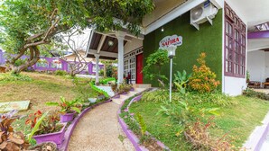A villa with a green wall, a red door, and a gravel pathway leading to the entrance. - RedDoorz Syariah near Balai Kota Batu (Batu)