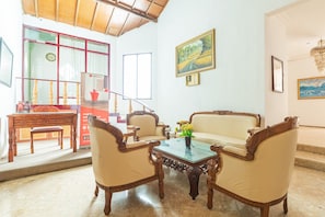 A spacious living room with a sofa, two armchairs, a coffee table, and a dining area with a table and chairs.