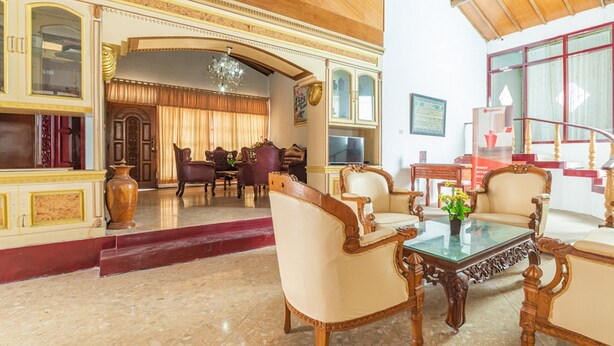 A spacious lobby with ornate furniture, a grand chandelier, and a red carpet leading to a staircase. - RedDoorz Syariah near Balai Kota Batu (Batu)