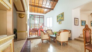 A spacious living room with a wooden ceiling, a fireplace, and a dining area with chairs and a table. - RedDoorz Syariah near Balai Kota Batu (Batu)