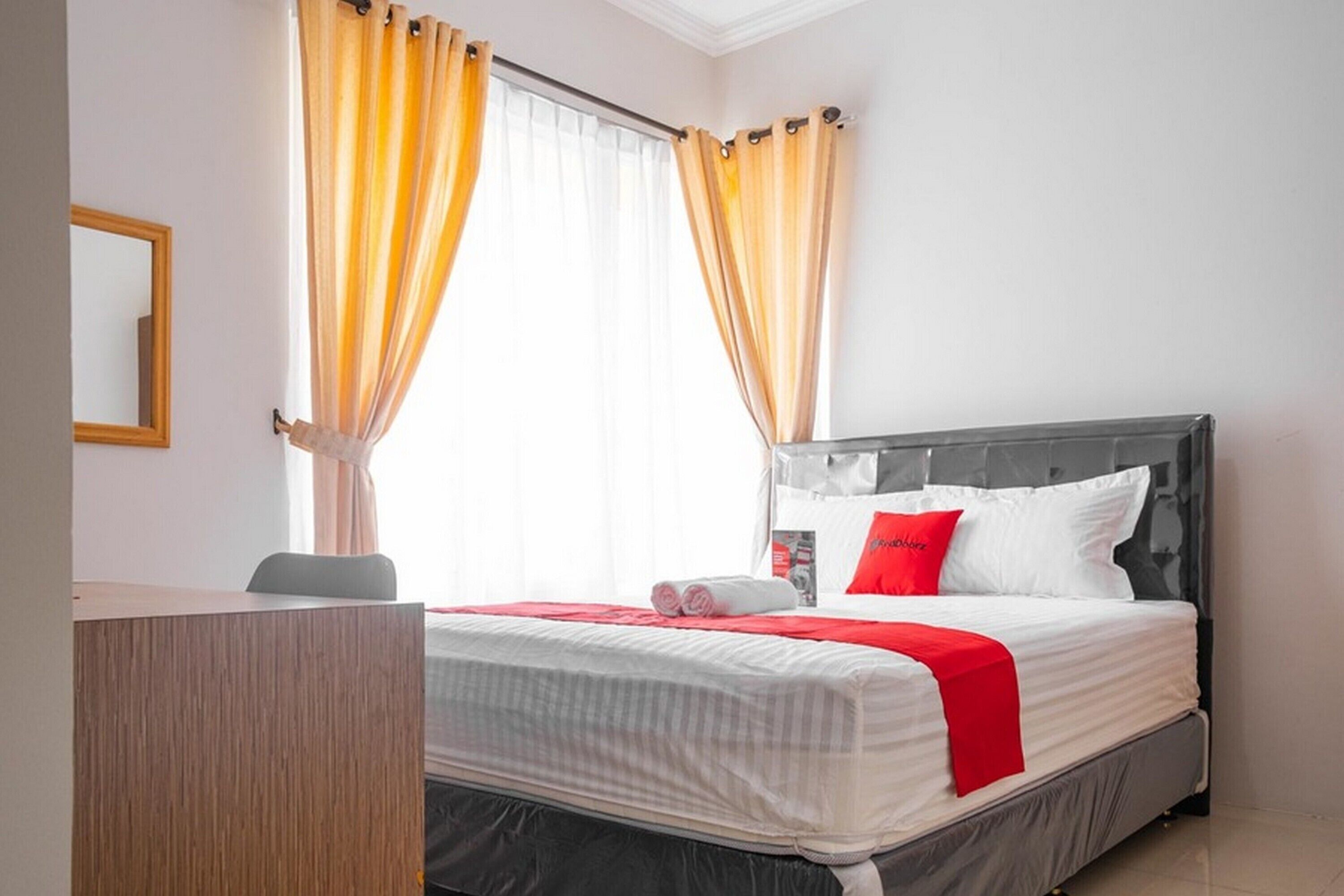 A hotel room with a bed, a desk, and a window with curtains.