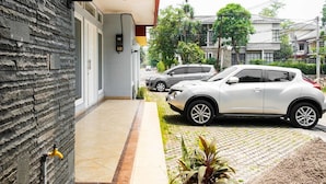 Una entrada de casa con un coche blanco estacionado a la derecha.