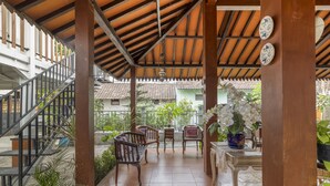 A covered patio area with wooden furniture, a staircase, and potted plants. - RedDoorz Syariah Near Wijilan 2 Yogyakarta (Yogyakarta)