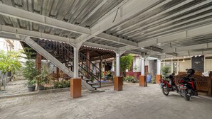 A covered outdoor area with a concrete floor, a staircase, and a parked motorcycle. - RedDoorz Syariah Near Wijilan 2 Yogyakarta (Yogyakarta)
