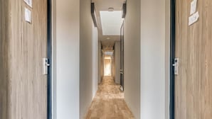 A hallway with wooden walls and a tiled floor, leading to a bright room at the end. - RedDoorz Plus near Gandaria City Mall 2 (Jakarta)