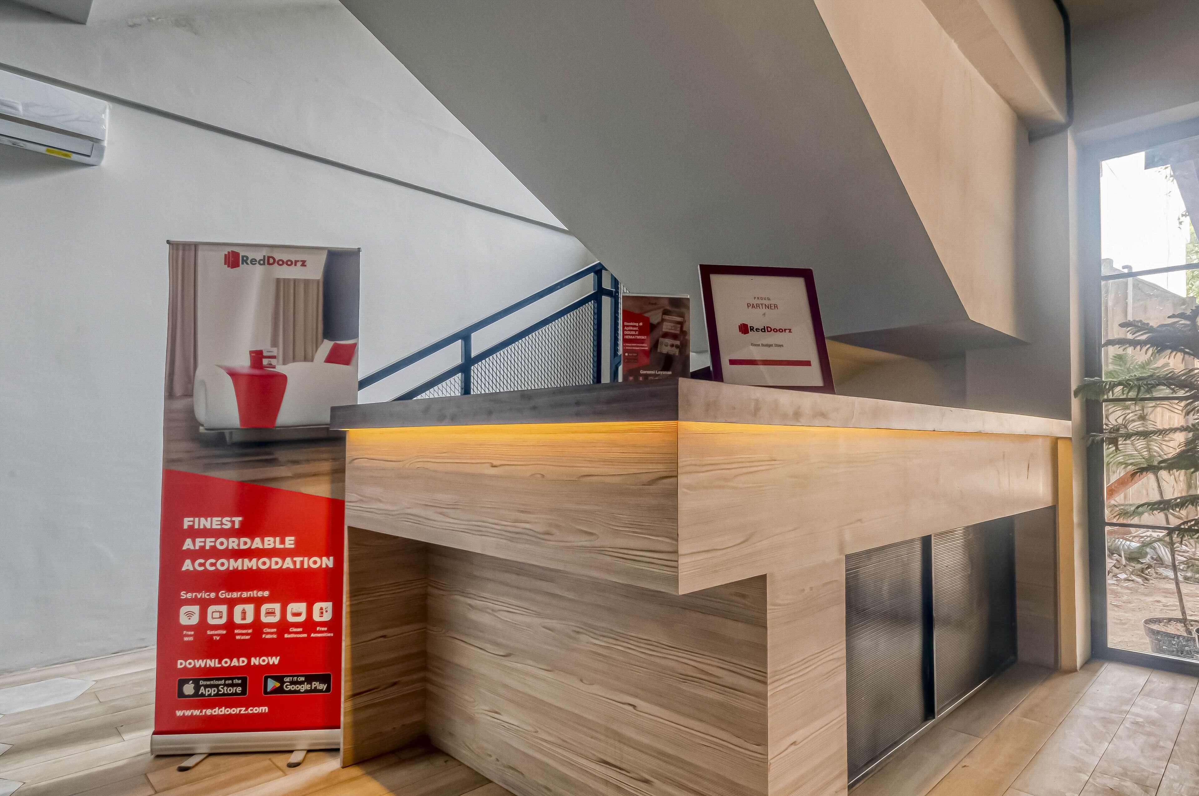 A reception desk with a wooden finish, a blue railing, and a sign for RedDoorz.