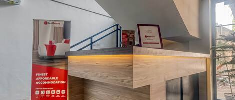 A reception desk with a wooden finish, a blue railing, and a sign for RedDoorz.