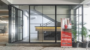 A modern hotel entrance with a glass door, a staircase, and a promotional poster for RedDoorz. - RedDoorz Plus near Gandaria City Mall 2 (Jakarta)