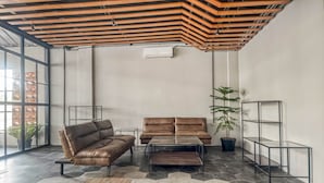 A modern living room with a brown leather sofa, a glass coffee table, and a wooden floor. - RedDoorz Plus near Gandaria City Mall 2 (Jakarta)