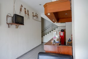 En hotellobby med en trappa, en receptionsdisk och en tv som är monterad på väggen.