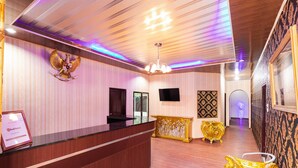 A reception area with a wooden reception desk, a chandelier, and ornate golden furniture. - RedDoorz Plus near Universitas Methodist Medan (Medan)