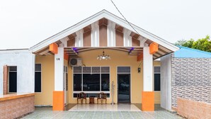 A building with a pitched roof, large windows, and a covered entrance area with chairs and a table. - RedDoorz Plus near Universitas Methodist Medan (Medan)
