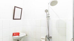 A bathroom with a sink, a mirror, and a shower. - RedDoorz Plus near Universitas Methodist Medan (Medan)
