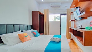 Une chambre d’hôtel moderne avec un grand lit, une tête de lit en bois, un bureau avec un ordinateur et une fenêtre avec des rideaux.