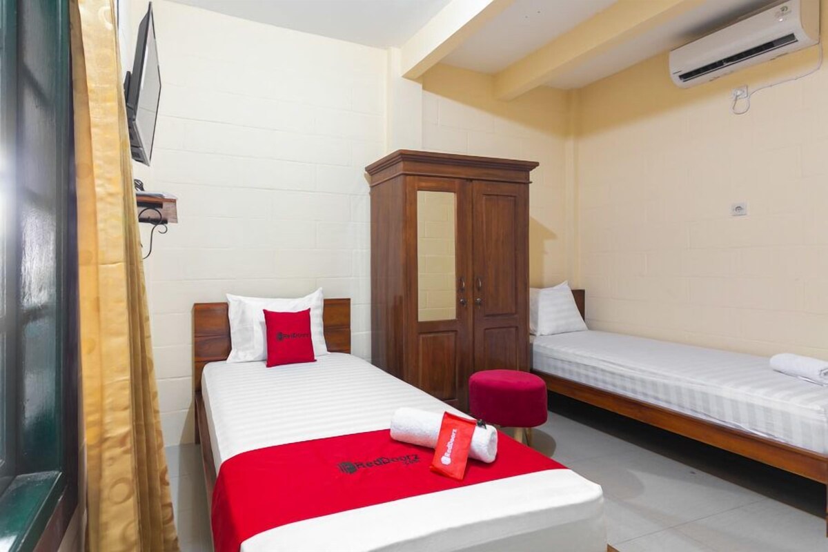 Une chambre d’hôtel équipée d’un lit, d’une armoire en bois, d’une télévision et d’un appareil de climatisation.