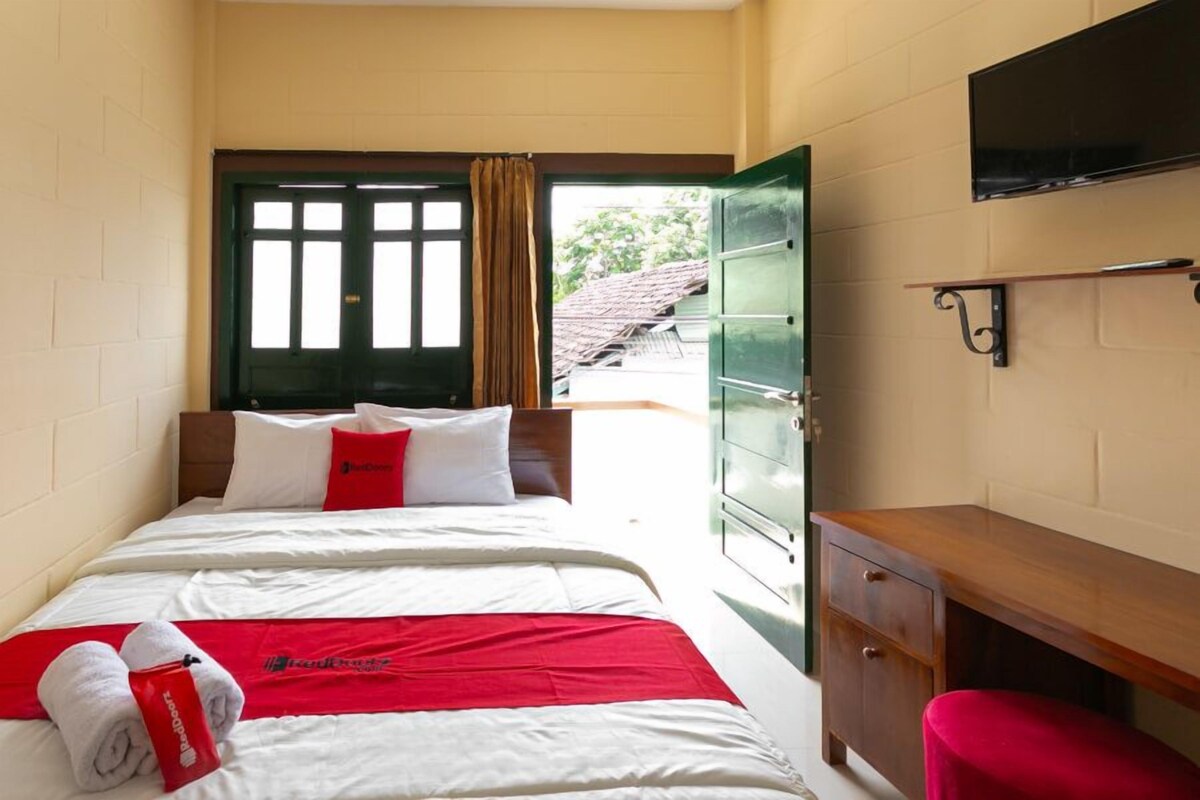 Une chambre d’hôtel équipée d’un lit, d’un bureau et d’un téléviseur fixé au mur.