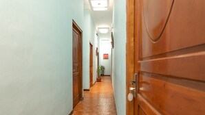 Un pasillo con puertas de madera, suelo de baldosas y una planta en maceta.