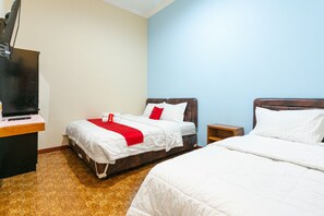 Een hotelkamer met twee bedden, een bureau met televisie en een klein nachtkastje.