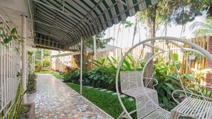 A covered outdoor area with a mosaic-tiled pathway, metal chairs, and lush greenery. - RedDoorz Syariah near Jalan Asahan Pematang Siantar (Pematangsiantar)