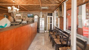 A reception area with a wooden ceiling, a reception desk, a refrigerator, and a seating area with chairs. - RedDoorz Syariah near Jalan Asahan Pematang Siantar (Pematangsiantar)