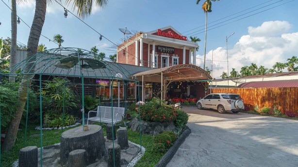 A hotel with a red facade, a covered entrance, and a car parked in front. - RedDoorz Syariah near Jalan Asahan Pematang Siantar (Pematangsiantar)