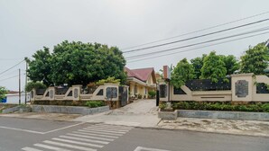 Zona residencial privada con camino pavimentado, paso de peatones y un árbol grande.