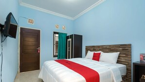 Una habitación de hotel con una cama, un televisor montado en la pared y una puerta.