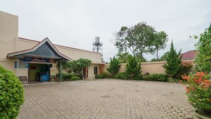 Un patio empedrado con baldosas hexagonales, rodeado de vegetación y un edificio con un letrero.