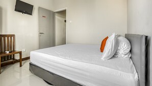 Une chambre à coucher avec un lit, un téléviseur fixé au mur et une porte donnant sur une autre pièce.