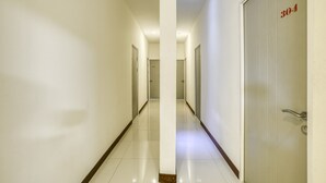 Un couloir d’hôtel avec un sol carrelé et des murs blancs, le tout d’une propreté impeccable. Une porte portant le numéro 304 est visible sur la droite.