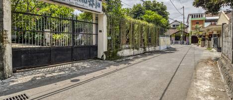 A gated entrance with a sign reading "Kedai Kambang" and a pathway leading into a residential area.