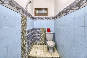 Ein Badezimmer mit blauen Fliesen, einer Toilette, einer Dusche und einem kleinen Fenster.