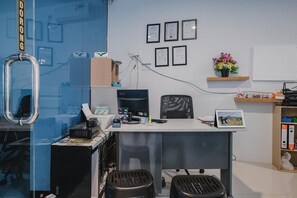 An office with a desk, computer, and two stools. There are certificates on the wall and a flower vase on a shelf. - RedDoorz Apartment @ Batam Centre 3 (Batam)