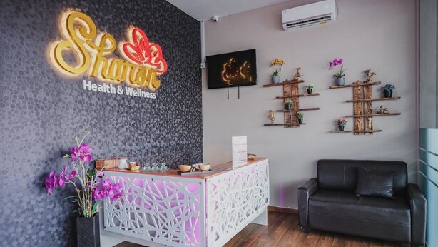 A reception area with a modern design, featuring a reception desk, a black leather sofa, and decorative shelves with plants. - RedDoorz Apartment @ Batam Centre 3 (Batam)