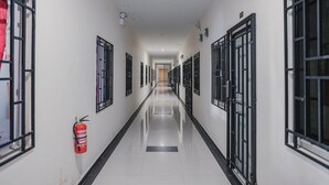A long, narrow hallway with doors on both sides, a fire extinguisher on the left, and a clean, reflective floor. - RedDoorz Apartment @ Batam Centre 3 (Batam)