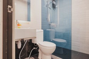 A modern bathroom with a white toilet, a sink, and a shower enclosure. - RedDoorz Apartment @ Batam Centre 3 (Batam)