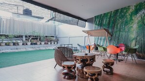 A modern indoor space with a wooden floor, a dining area with a table and chairs, and a view of a garden with potted plants. - RedDoorz Apartment @ Batam Centre 3 (Batam)