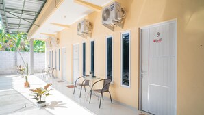 A hallway with multiple doors, air conditioning units, potted plants, and a tiled floor. - RedDoorz Syariah @ Winong Nganjuk (Nganjuk)