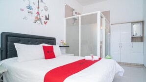 A hotel room with a bed, a wardrobe, a shower area, and a wall with Paris-themed decorations. - RedDoorz Syariah @ Winong Nganjuk (Nganjuk)