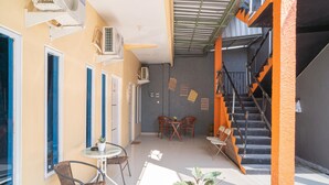 A small, brightly lit room with a table and chairs, a staircase, and a window. - RedDoorz Syariah @ Winong Nganjuk (Nganjuk)