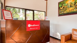 A reception desk with a RedDoorz sign, a framed certificate, and a painting on the wall. - RedDoorz Syariah near Gor Ken Arok (Malang)