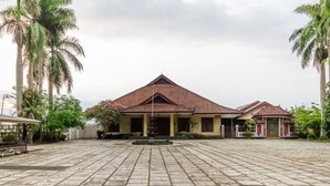 A courtyard with a building featuring a tiled roof and a central fountain. - RedDoorz Syariah near Gor Ken Arok (Malang)