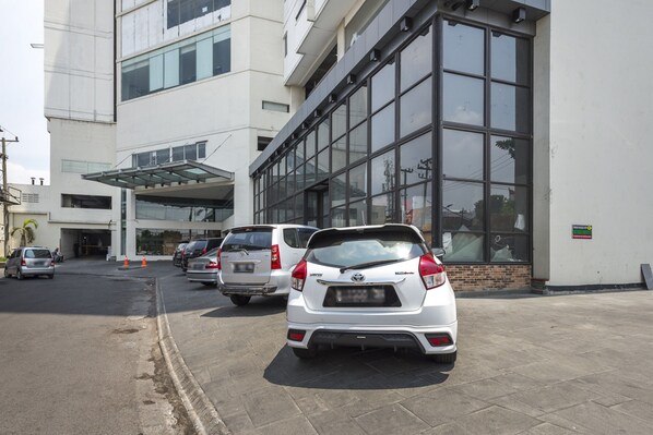 A parking lot with several cars parked in front of a building with large windows and a covered entrance.